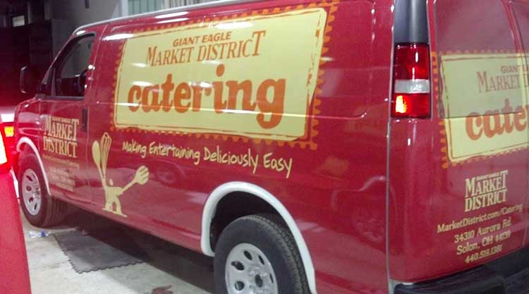 Deep red cargo van wrapped for Giant Eagle Market District catering, with gold script lettering across the side panel.