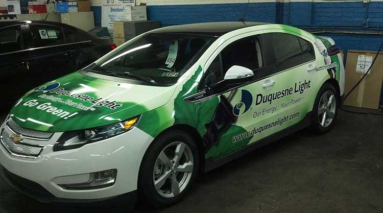 Chevrolet Volt wrapped in green and white for Duquesne Light with Go Green lettering on the hood and the company logo along the doors.