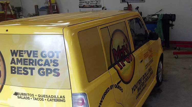 Bright yellow Scion xB wrapped for Moe's Southwest Grill, with promotional lettering across the rear glass and a menu list along the lower panel.