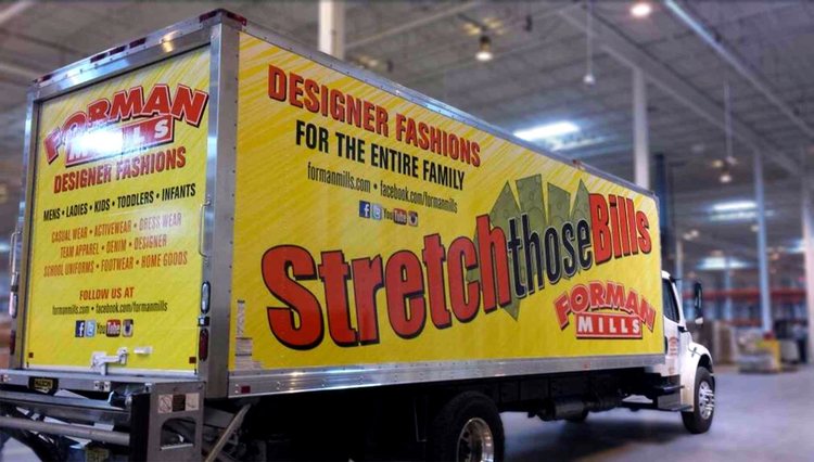 Box truck wrapped for Forman Mills in bright yellow, with large Stretch Those Bills lettering along the side and a product list across the rear door.